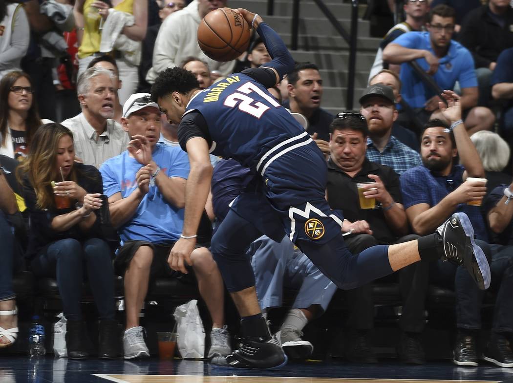 Denver Nuggets guard Jamal Murray dives into the fans in the courtside seats to save a loose ba ...