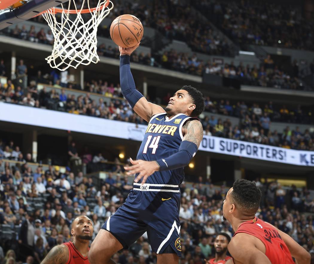 Denver Nuggets guard Gary Harris, center, goes up for a basket between Portland Trail Blazers g ...