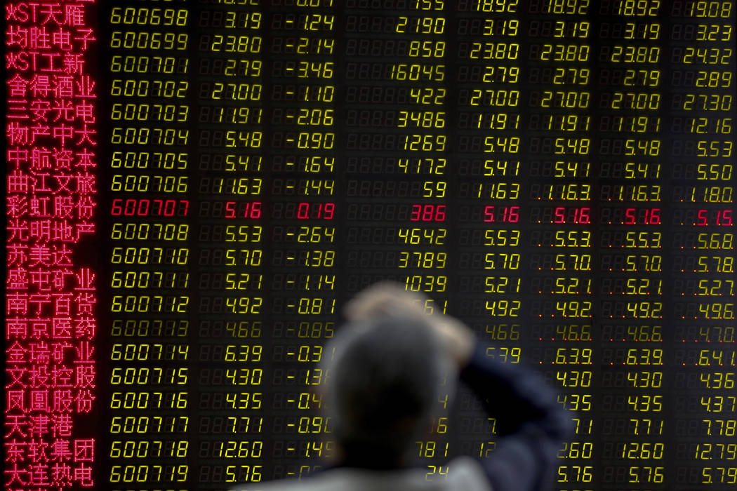 A man rubs his forehead as he monitors stock prices at a brokerage house in Beijing, Monday, Ma ...