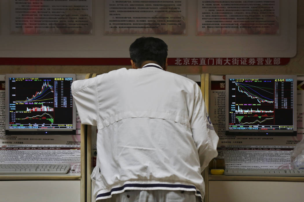 A man checks stock prices at a brokerage house in Beijing, Monday, May 13, 2019. Shares were mo ...