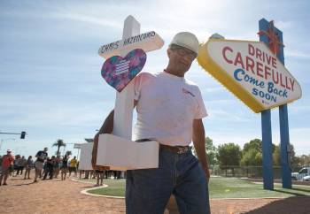 Greg Zanis, of Aurora, Ill., carries one of 58 crosses he placed near the Welcome to Fabulous L ...