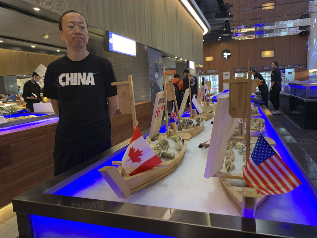 A shopper eyes display of seafood including oysters from the U.S. at a supermarket in Beijing o ...