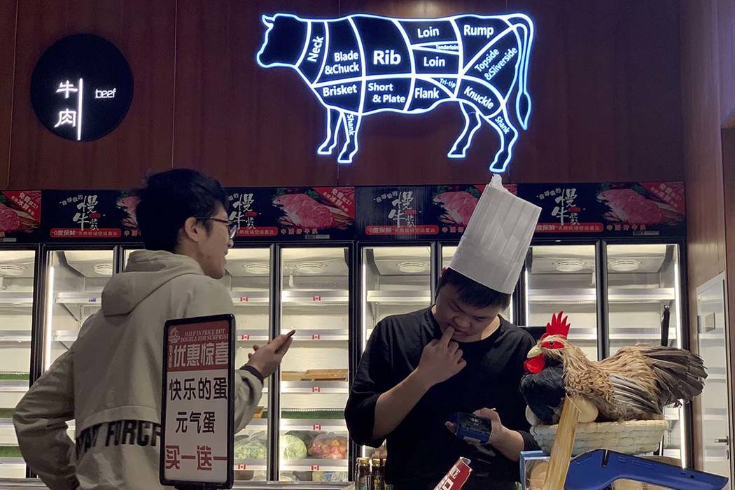 A worker at the imported beef section of a supermarket that used to carry U.S. products chats w ...