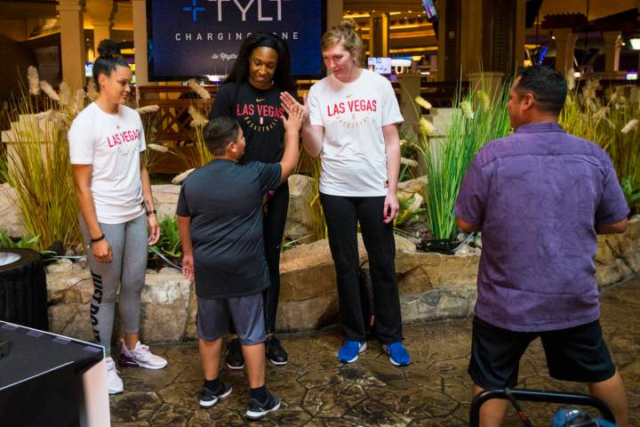 Braeden Sada, 11, high-fives Las Vegas Aces player Carolyn Swords, right, as players Kayla McBr ...