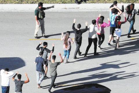 Students hold their hands in the air as they are evacuated by police from Marjorie Stoneman Dou ...
