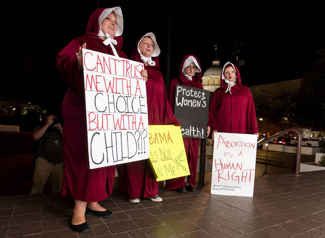 Anti-abortion ban bill protesters, dressed as handmaids, from left, Bianca Cameron-Schwiesow, K ...