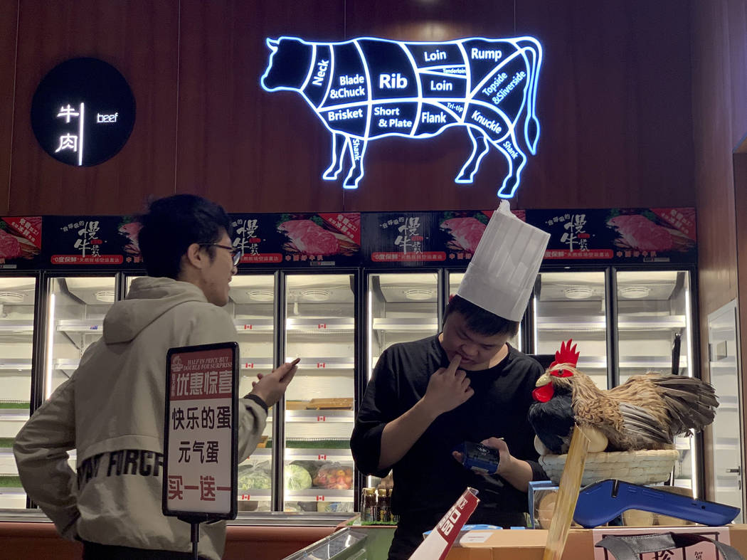A worker at the imported beef section of a supermarket that used to carry U.S. products chats w ...
