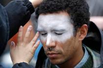 A man, who declined to be identified, has his face painted to represent efforts to defeat facia ...