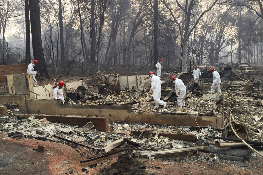 In this Nov. 15, 2018 file photo, volunteer rescue workers search for human remains in the rubb ...