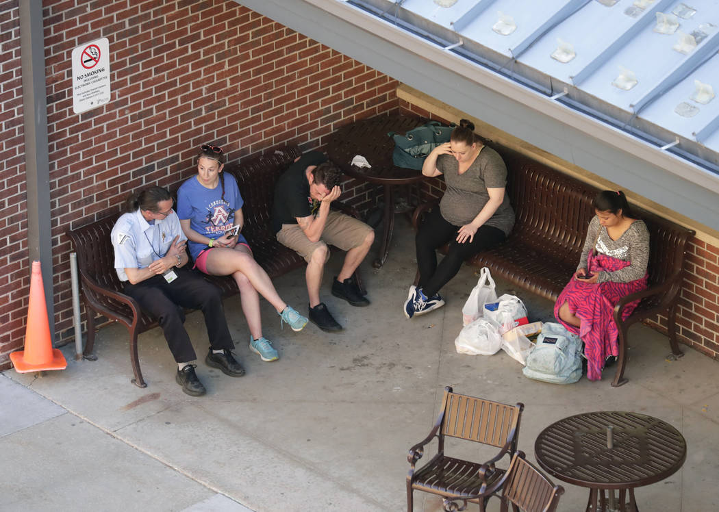 In this Wednesday, May 15, 2019 photo, people wait as authorities investigate the scene of a sh ...