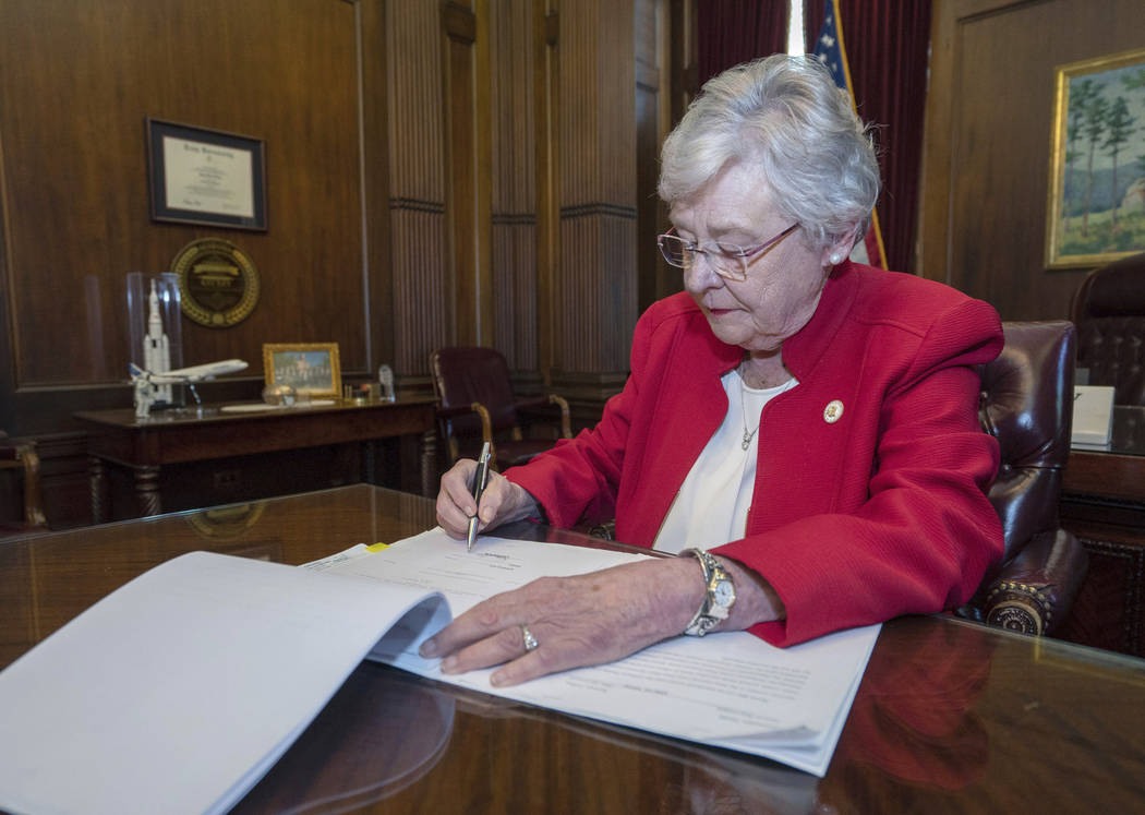 This photograph released by the state shows Alabama Gov. Kay Ivey signing a bill that virtually ...