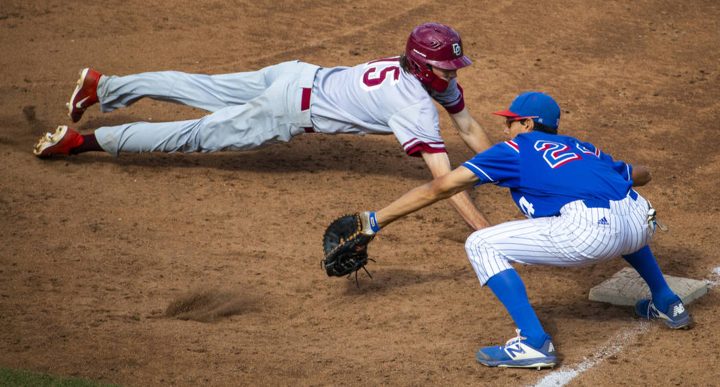 Desert Oasis runner Campbell Holt (15) dives safely back to first base past Reno's Skylar Hales ...