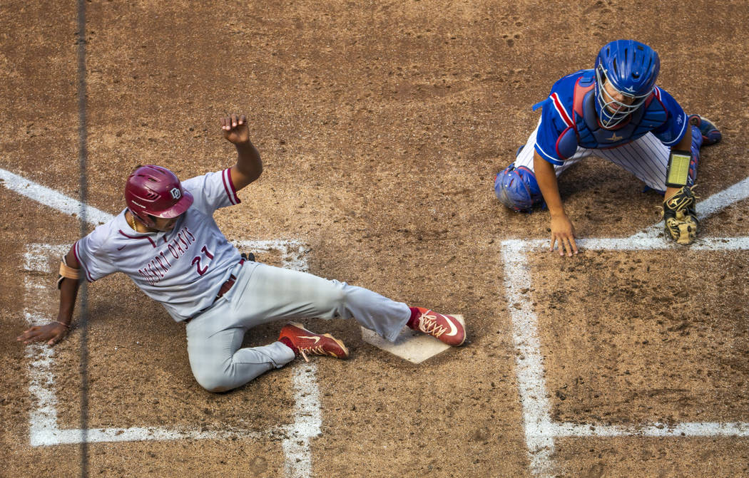 Desert Oasis runner Jacob Walsh (21) slides home safely past Reno catcher Lane Oliphant (28) in ...