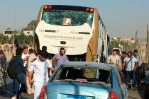 Police inspect a car and a bus that were damaged by a bomb, in Cairo, Egypt, Sunday, March 19, ...