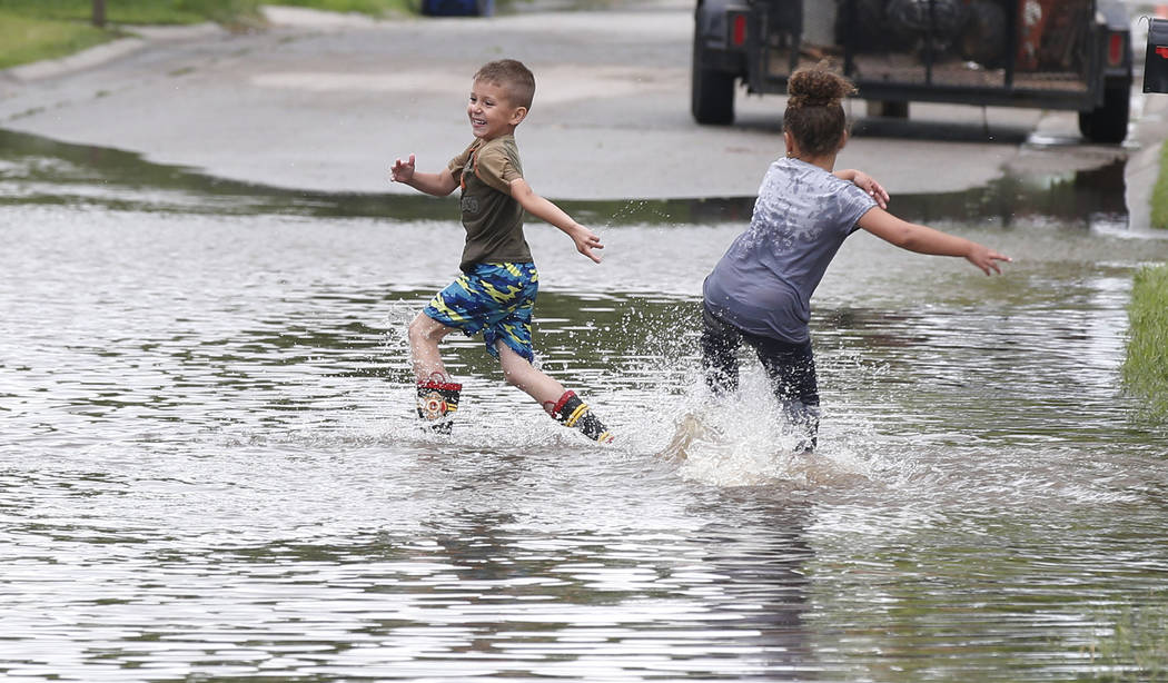 Kayden Evans, left, 6, and Keely Younger, 6, play in the water on a flooded street in El Reno, ...