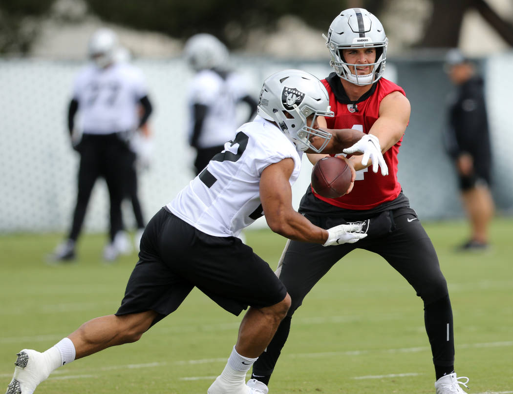 Oakland Raiders quarterback Derek Carr, right, hands off the football to running back Doug Mart ...