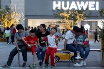 In a photo taken Monday, May 20, 2019, residents enjoy a cool evening near a Huawei store in Be ...