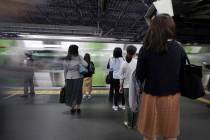 Commuters wait to get on a train at a station Wednesday, May 22, 2019, in Tokyo. A police-devel ...