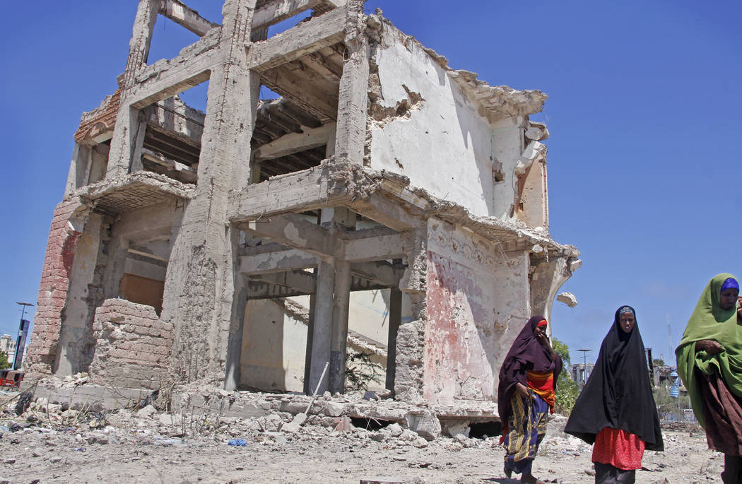 Somali women walk past a destroyed building after a suicide car bomb attack in the capital Moga ...
