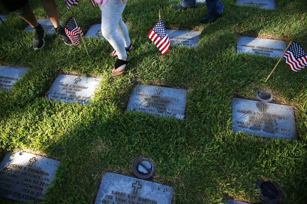 American flags decorate gravesites during the annual “Flag-In” event at the South ...