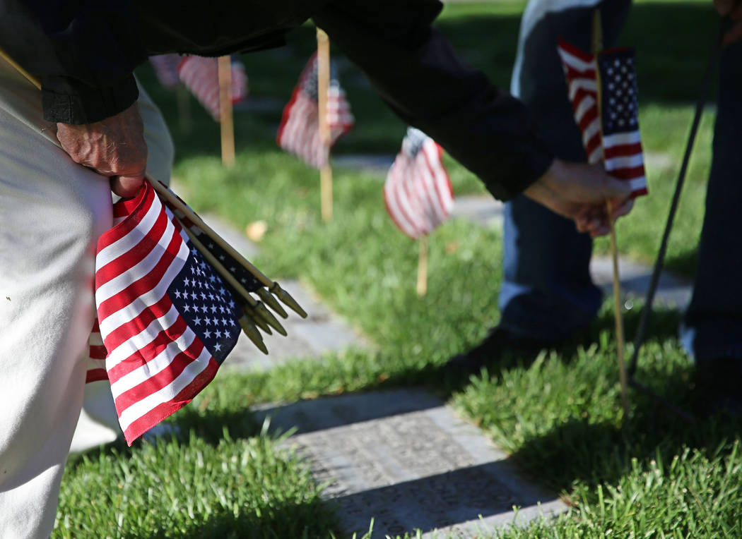 Ray Pelletier, U.S. Army veteran, places an American flag on a gravesite during the annual &#x2 ...