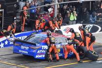 Crew members lift Martin Truex Jr.'s car to change a flat tire during a NASCAR Cup Series auto ...
