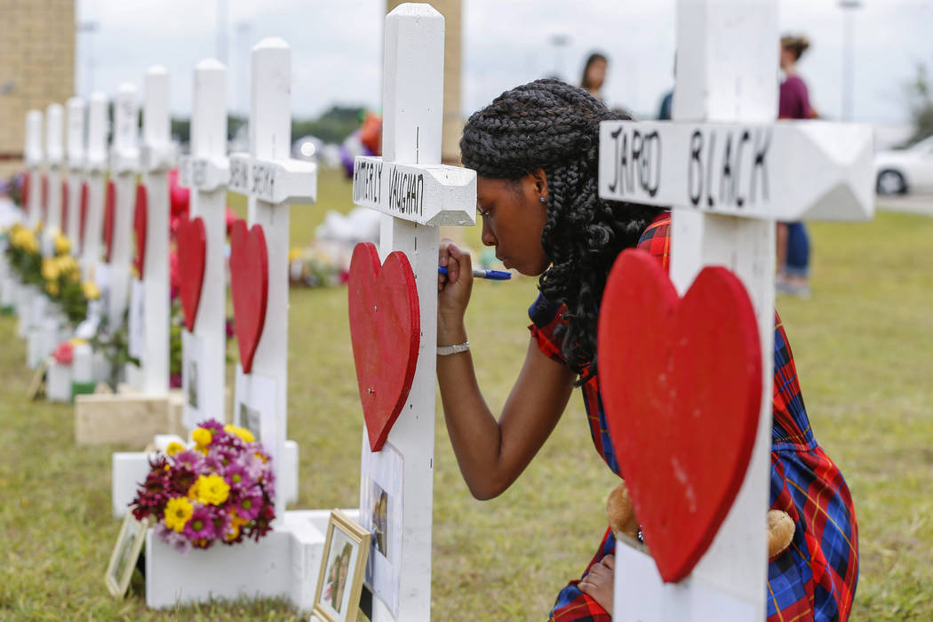 Santa Fe High School freshman, Jai Gillard writes messages on each of the 10 crosses representi ...