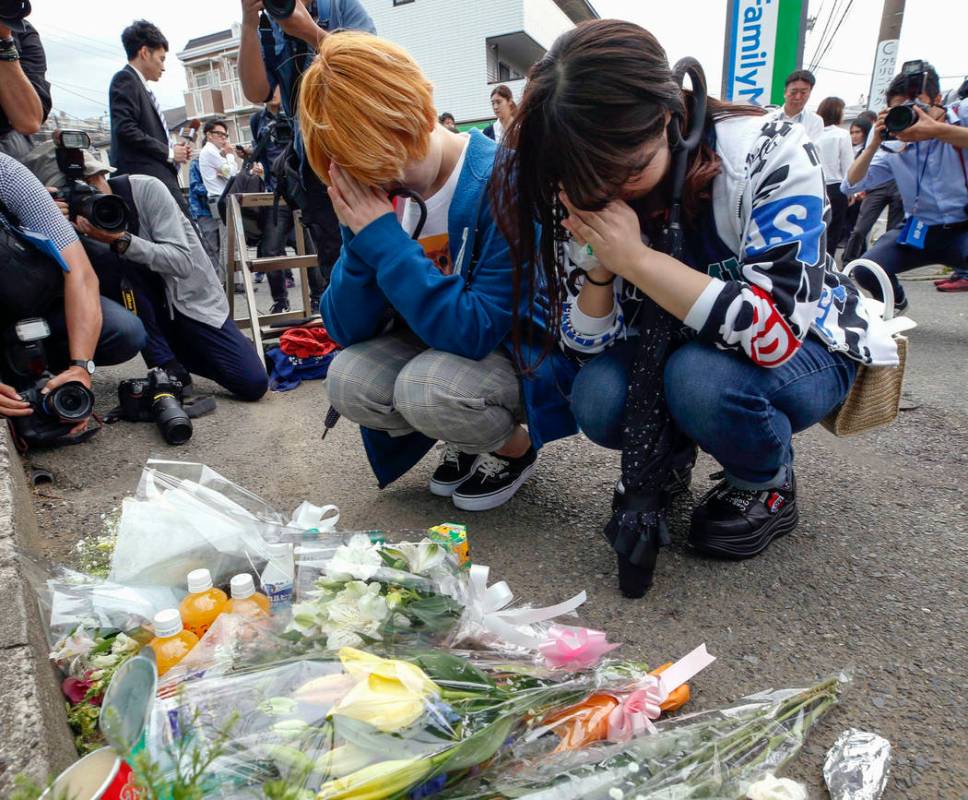 Women pray after offering flowers near the scene where a man wielding a knife attacked commuter ...