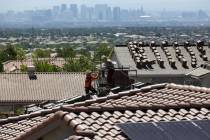 Construction workers set bundles of tile on the roof of an under-construction house in the mast ...