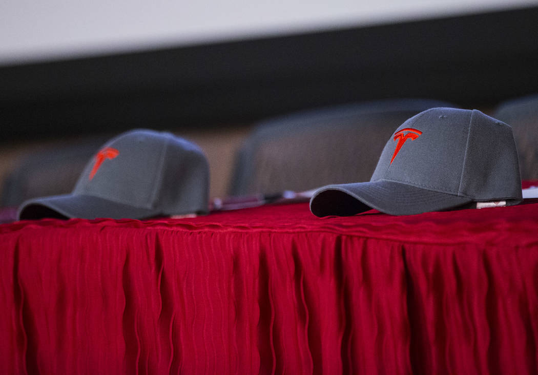 Tesla hats sit on a table at the start of a signing ceremony for recent high school graduates t ...