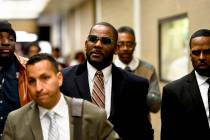 Musician R. Kelly, center, leaves the Daley Center after a hearing in his child support case, M ...