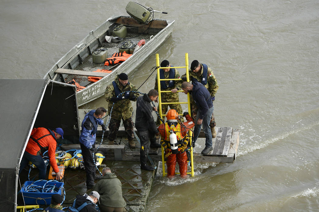 A diver descends a ladder to dive to the wreckage as rescuers work to prepare the recovery of t ...