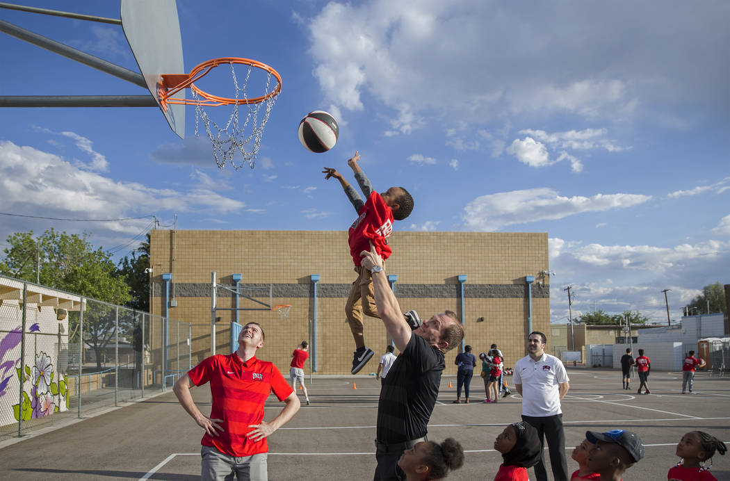 UNLV head basketball coach T.J. Otzelberger, middle, gives a boost to Ryan Fraley, 4, during a ...