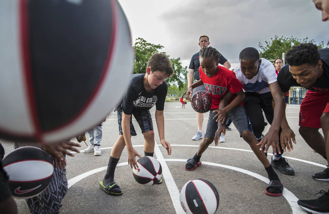 Kids with the Nevada Youth Network practice dribbling during a youth clinic hosted by UNLV head ...