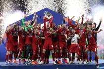 Liverpool's Jordan Henderson lifts the trophy to celebrate with his teammates winning the Champ ...