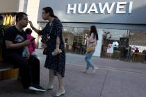 A woman adjusts the glasses of a man outside a Huawei store on May 20, 2019, in Beijing. The wo ...