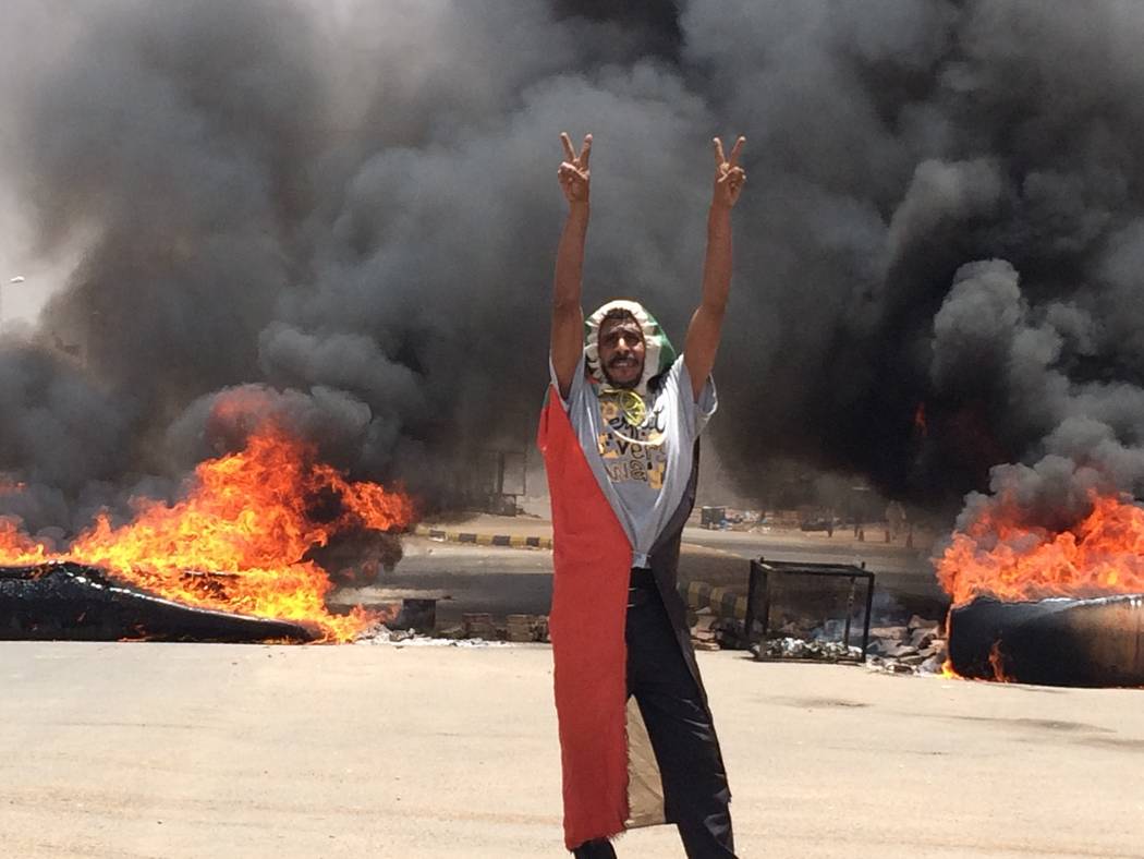 A protester flashes the victory sign in front of burning tires and debris on road 60, near Khar ...