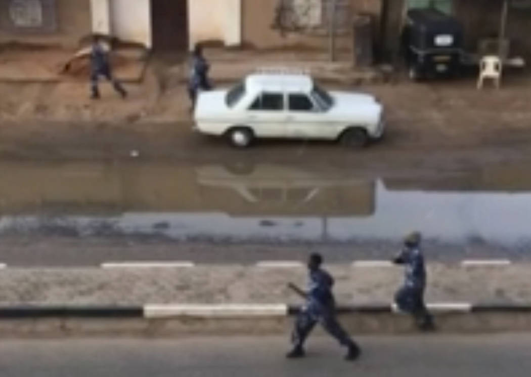 In this image made from video, Police officers running down a street in Khartoum, Sudan, on Mon ...