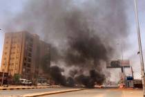 Burning tires set by protesters produce black smoke on road 60, near Khartoum's army headquarte ...