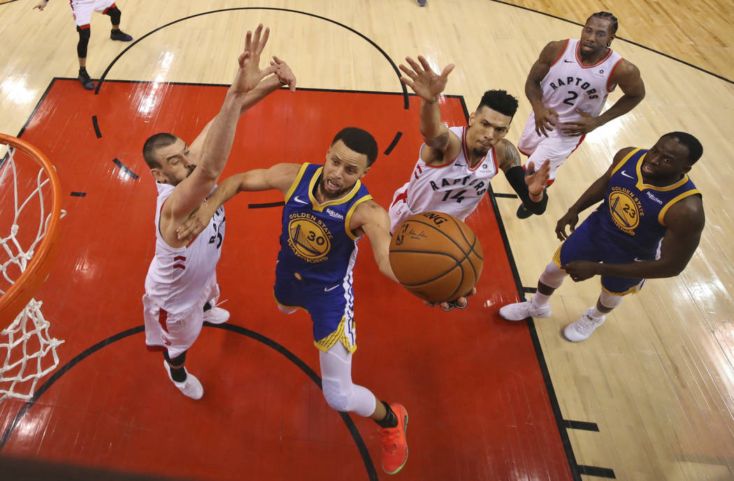 Golden State Warriors' Stephen Curry (30) drives to the basket between Toronto Raptors' Marc Ga ...