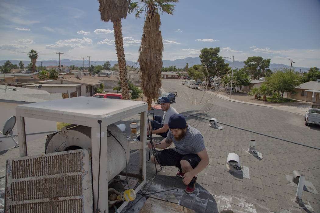 Jose Jesus Gomez, 23, and Sergio Soderanis, 27, fix the swan cooler on their roof as temperatur ...
