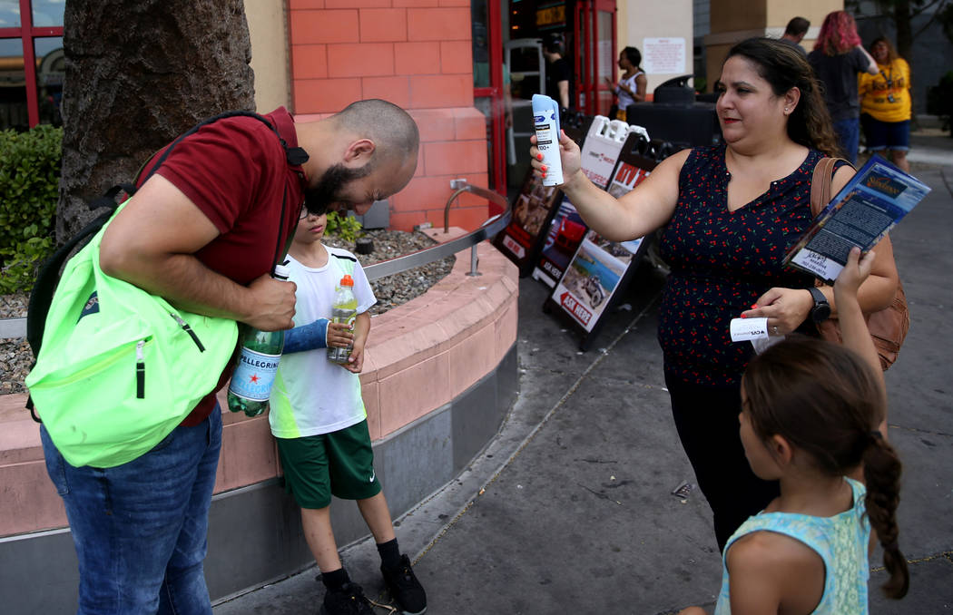 Julie Benavides of San Antonio, Texas, sprays sunscreen on her husband Jose with their children ...