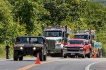 Military police direct traffic along Route 293 near the site where an armored personnel vehicle ...