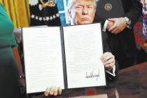 President Donald Trump holds up an executive order after his signing the order in the Oval Offi ...