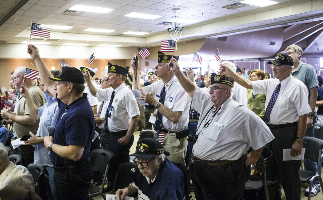 Veterans raise their flags as "God Bless the USA" is sung during a ceremony commemora ...