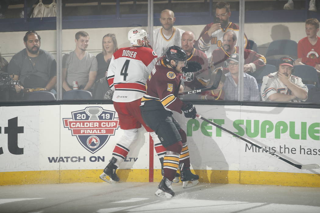 Chicago Wolves left wing Tye McGinn (5) avoids a check from Charlotte Checkers defenseman Josia ...