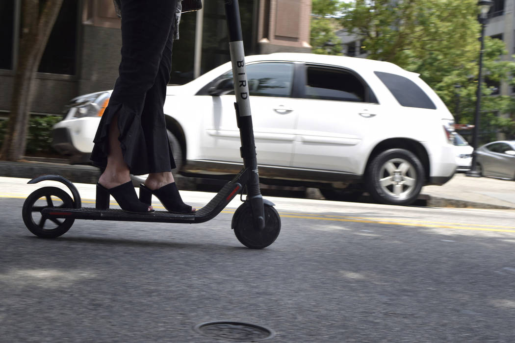 A woman rides an electronic scooter in downtown Raleigh, N.C., in May 2019. (AP Photo/Amanda Mo ...