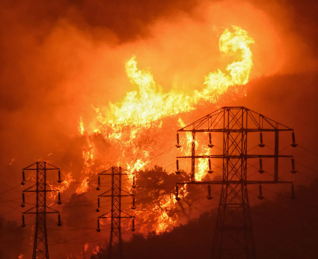 Flames burn near power lines in Sycamore Canyon near West Mountain Drive in Montecito, Calif., ...