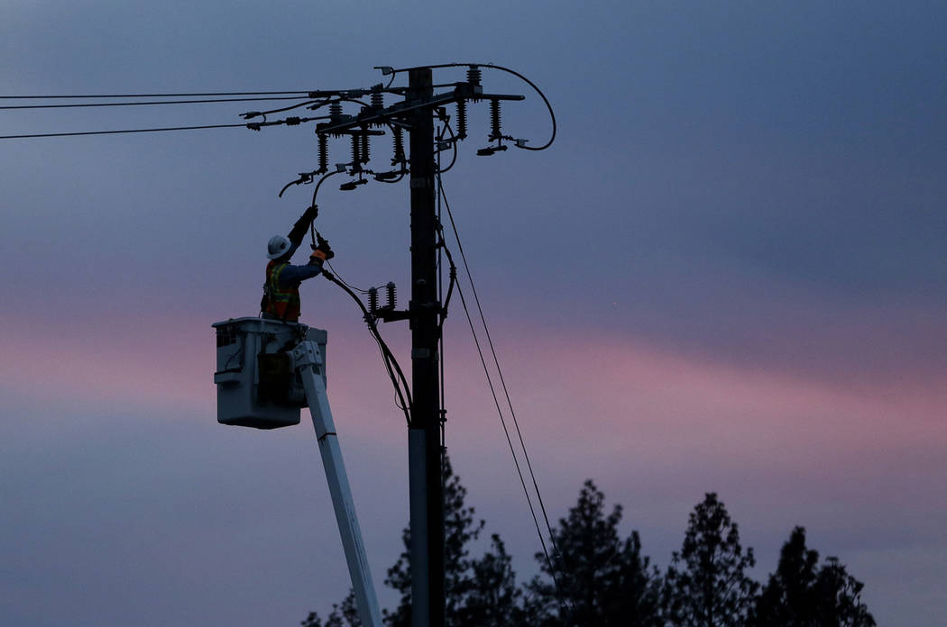 A Pacific Gas & Electric lineman works to repair a power line in fire-ravaged Paradise, Calif., ...