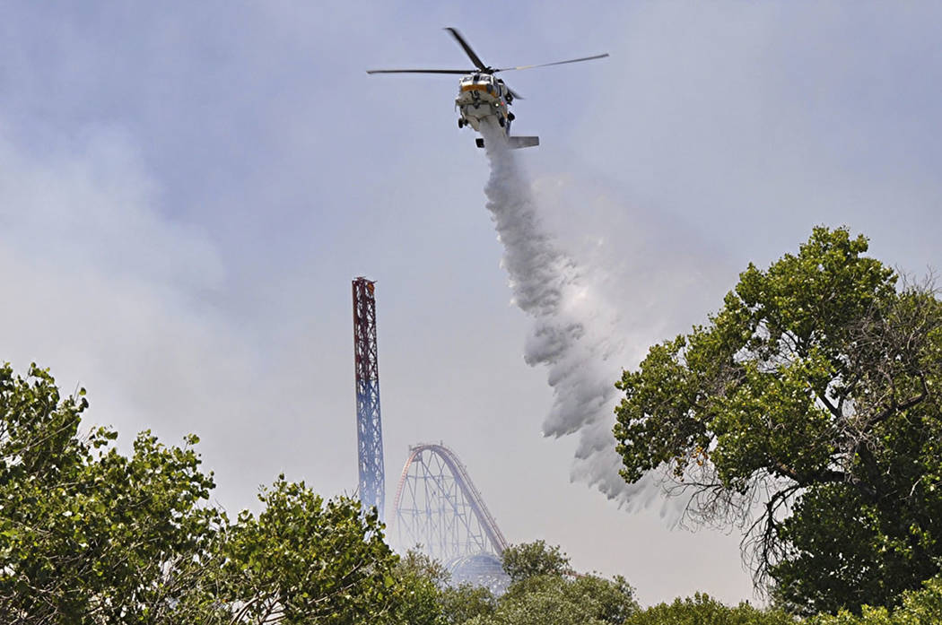 Los Angeles County Fire helicopter drops water on brush fire burning close to Six Flags Magic M ...